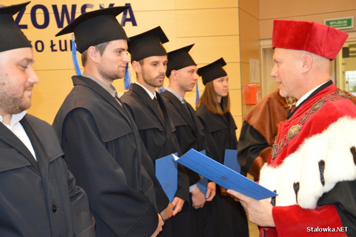 Prorektor profesor Jarosław Sęp wręcza absolwentom dyplomy ukończenia studiów inżynierskich.